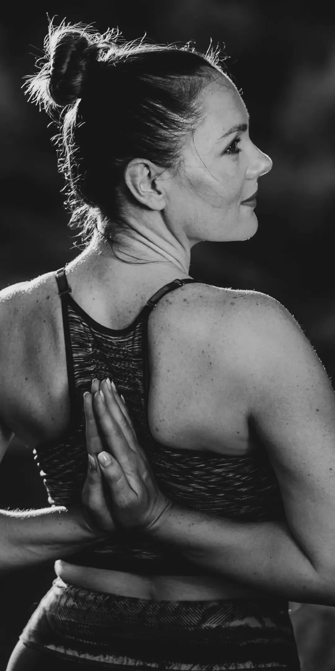 Joga kręgosłupa i bioder w Teho Sport w Trzebownisku – kobieta w pozycji stojącej z dłońmi złożonymi za plecami, zdjęcie czarno-białe